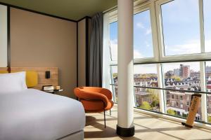 a hotel room with a bed and a chair and windows at Avani Museum Quarter Amsterdam Hotel - previously NH Amsterdam Museum Quarter in Amsterdam