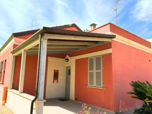 una casa rossa e bianca con portico di Oasi sul Mare - A soli 1 Minuto a Piedi dalla Spiaggia a Senigallia