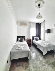 Cette chambre comprend 2 lits et une fenêtre. dans l'établissement Merkez Kumsal Pansiyon, à Bodrum City