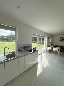 a kitchen with white cabinets and a large window at Dom wakacyjny z sauną i ogrodem na wyłączność in Drawno +50 photos