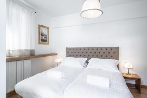 dwa łóżka w białej sypialni z dwoma lampami w obiekcie Chalet Falorie w mieście Cortina dʼAmpezzo