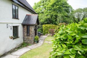 een tuin met een klein huis met een heg bij Charming Guest House in Cornish Countryside in Bodmin