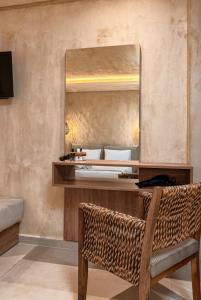 a dressing table with a mirror and a wicker chair at Odyssey Accommodation - Apartments in Pefkochori