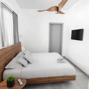 a white bedroom with a bed and a tv at Viva Mare Studios in Astypalaia Town