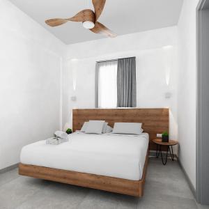 a white bedroom with a bed and a ceiling fan at Viva Mare Studios in Astypalaia Town