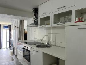 una cocina con armarios blancos y fregadero en Apartment Kuk, en Split