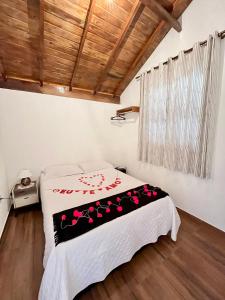 Un dormitorio con una cama con una manta blanca y negra. en Recanto do Santista, chalé 02, en Camanducaia