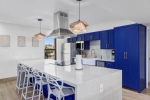 a kitchen with blue cabinets and a kitchen island with stools at Saida II Beachfront Oasis in South Padre Island