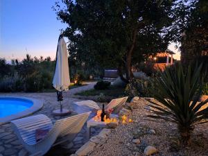 eine Terrasse mit einem Sonnenschirm und Stühlen neben einem Pool in der Unterkunft Villa Cesarica Novalja in Novalja