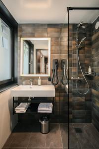 La salle de bains est pourvue d'un lavabo et d'une douche. dans l'établissement Hota Hotel Saint-Imier, à Saint-Imier