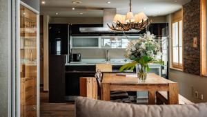 una cocina con una mesa de madera y un jarrón de flores en Casa Della Luce Apartments, en Zermatt