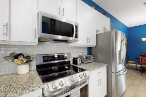 a kitchen with white cabinets and a stainless steel refrigerator at Desert Sun Retreat in Sun City