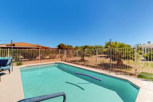 a swimming pool with a chair and a fence at Desert Sun Retreat in Sun City