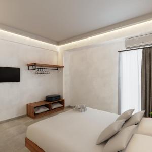 a bedroom with a white bed and a tv at Viva Mare Studios in Astypalaia Town