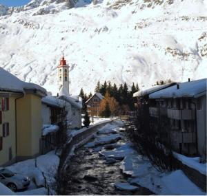 uma montanha coberta de neve com um edifício e uma igreja em Boutique Hotel The River House em Andermatt