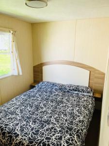 a bedroom with a bed with a blue and white comforter at Meadow View Horizon Static Caravan in Barnstaple