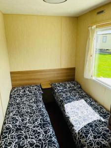 a small room with two beds and a window at Meadow View Horizon Static Caravan in Barnstaple