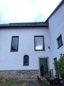 a white house with black windows and a patio at Ferienzimmer Geyersberg in Kirschroth