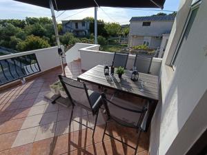 a wooden table and chairs on a balcony with an umbrella at Apartment Martina in Rab