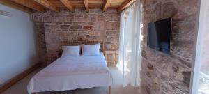奧瑞比克的住宿－Geta Orebić，一间卧室设有一张床,石墙上配有电视。