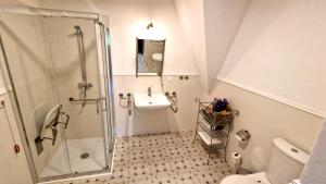 uma casa de banho branca com um chuveiro e um lavatório. em Hotel Charlotta em Jedlina-Zdrój