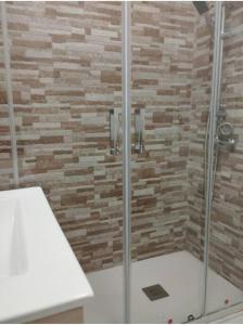 a bathroom with a shower with a stone wall at Apartamento Morriña in Brion