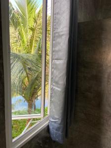 ein Fenster mit Blick auf eine Palme in der Unterkunft Green Mountain Resort Koh Yao in Ko Yao Yai