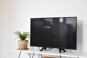 a flat screen tv sitting on a white stand with a plant at Cosy two bedroom in Romford in Romford