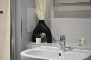 a bathroom with a sink and a black vase at Cosy two bedroom in Romford in Romford