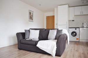 Una sala de estar con un sofá y una cocina. en Spacious 1BR in Romford - Near Elizabeth Line, en Romford