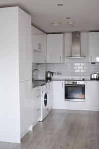a kitchen with white cabinets and a washing machine at Stylish 2BR - 1 minute walk from Elizabeth Line in Romford +11 photos