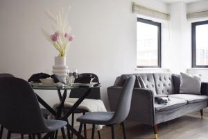 a living room with a couch and a table with chairs at Stylish 2BR - 1 minute walk from Elizabeth Line in Romford