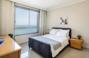 een slaapkamer met een bed en een groot raam bij Almog Tower in Haifa