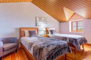 2 camas en una habitación con silla y ventana en Refúgio do Lourinho, en Funchal