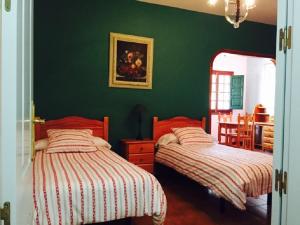 Alojamiento Rural La Montaña في تيخيدا: سريرين في غرفة نوم مع جدران خضراء