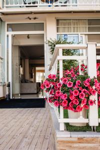 un banc blanc avec un panier de fleurs rouges dans l'établissement Hotel Marialena, à Potos