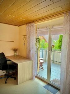 ein Büro mit einem Schreibtisch und einer Glasschiebetür in der Unterkunft neXt doOr Donau Gästezimmer und Suite in Wurmlingen