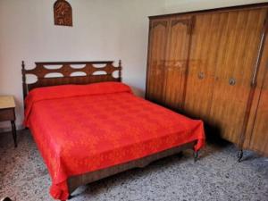 una camera con letto rosso e armadio in legno di Appartamento a Matino
