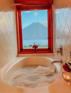 a bathroom with a bath tub with a window at Casa Mariposa San Marcos Atitlán Lakefront Retreat in San Marcos La Laguna