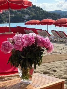 ル・ラヴァンドゥーにあるLe Lavandou St Clairのビーチのテーブルの上に置かれたピンクの花の入った花瓶