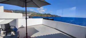 a balcony with an umbrella and a view of the ocean at Furna Blue View in Lagoa