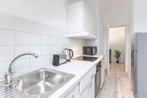 a white kitchen with a sink and a refrigerator at Stilvolle Ferien-und Monteurunterkunft Leverkusen in Leverkusen