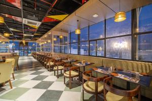 a restaurant with tables and chairs and large windows at Monday Hotels Amalapuram Heights in Amalāpuram