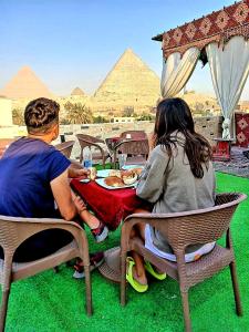 duas pessoas sentadas numa mesa em frente às pirâmides em Arena pyramids view no Cairo