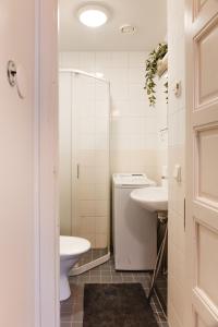 La salle de bains blanche est pourvue d'un lavabo et de toilettes. dans l'établissement Nordstay - Bright Studio in the heart of Helsinki self check-in, à Helsinki