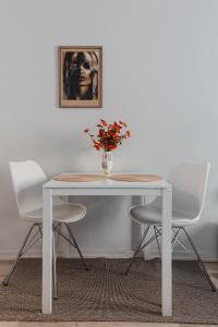 une table blanche avec deux chaises et un vase avec des fleurs dans l'établissement Nordstay - Bright Studio in the heart of Helsinki self check-in, à Helsinki