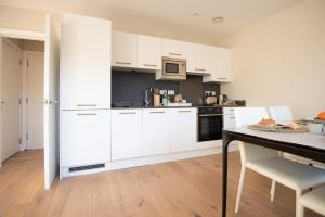 uma cozinha branca com armários brancos e uma mesa em Dream Stays Bath - John Street em Bath