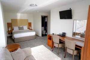 a hotel room with a bed and a desk and a bed and a couch at Hardgate House Hotel in Clydebank