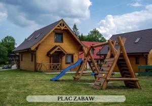 einen Spielplatz vor einem Holzhaus in der Unterkunft Michałówka Pokoje i Domki in Karłów