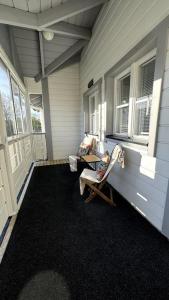 Un porche con una silla y una mesa y ventanas. en Old Town - 2 bedrooms with sauna, en Kokkola